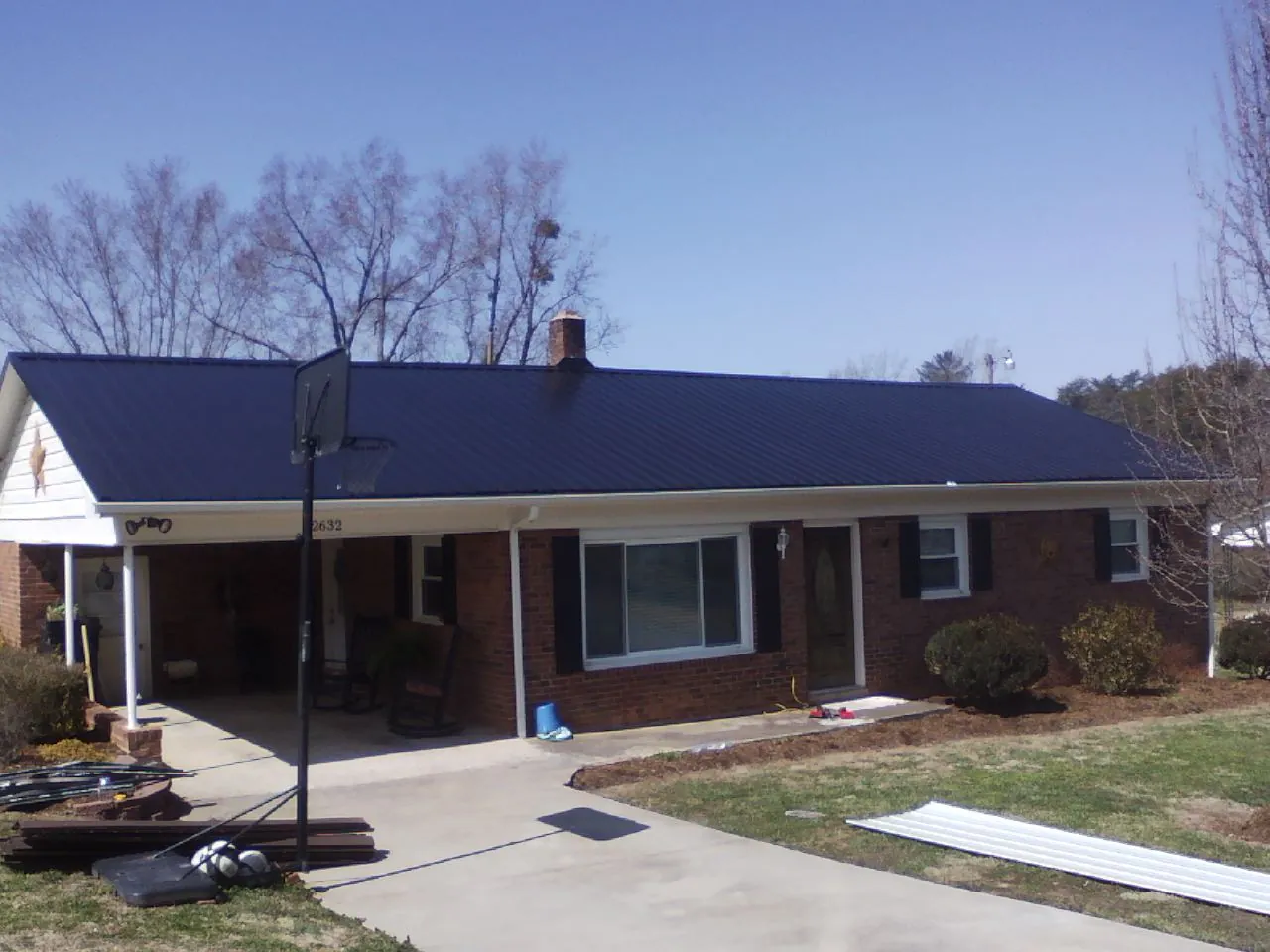 Finished dark blue metal roof on a brick ranch with a carport in Sisters