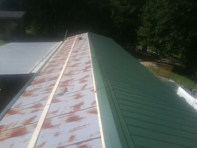 Old rusted panels beside newly installed green metal roofing — Wind Damage Roof Repair by Roofing Brothers in Sisters