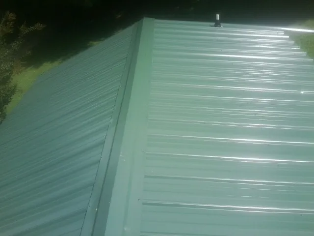 New green metal panels meeting at the ridge of a roof — Flat Roof Repair work by our crew in Sisters