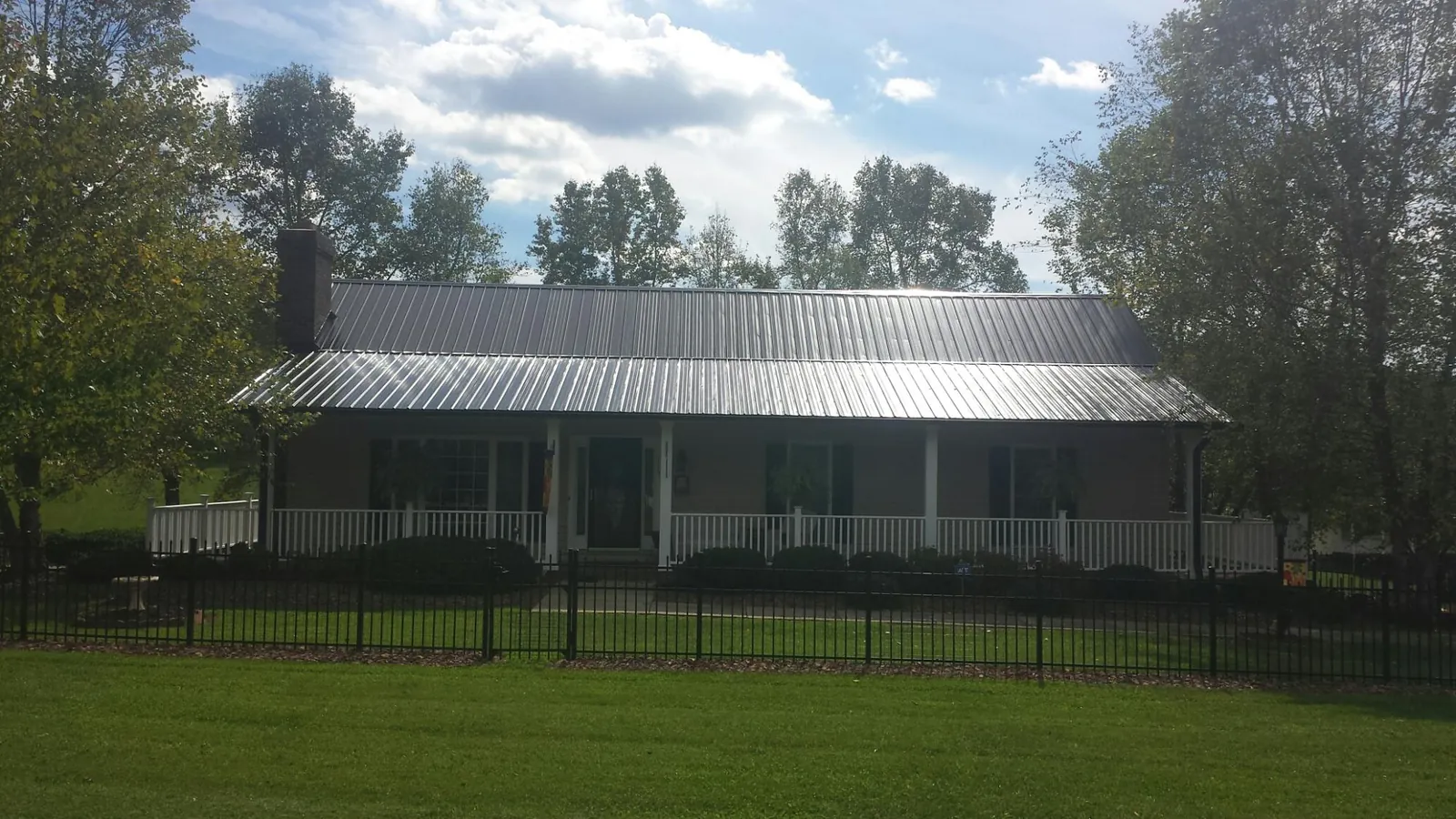 Gray metal roof on a brick ranch with a full width front porch — Gutter Guard Installation work by our crew in Sisters