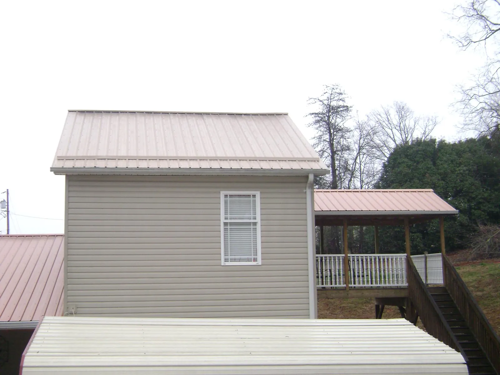 Tan metal roofs on a two story addition and attached porch, from a Roof Replacement job in Sisters