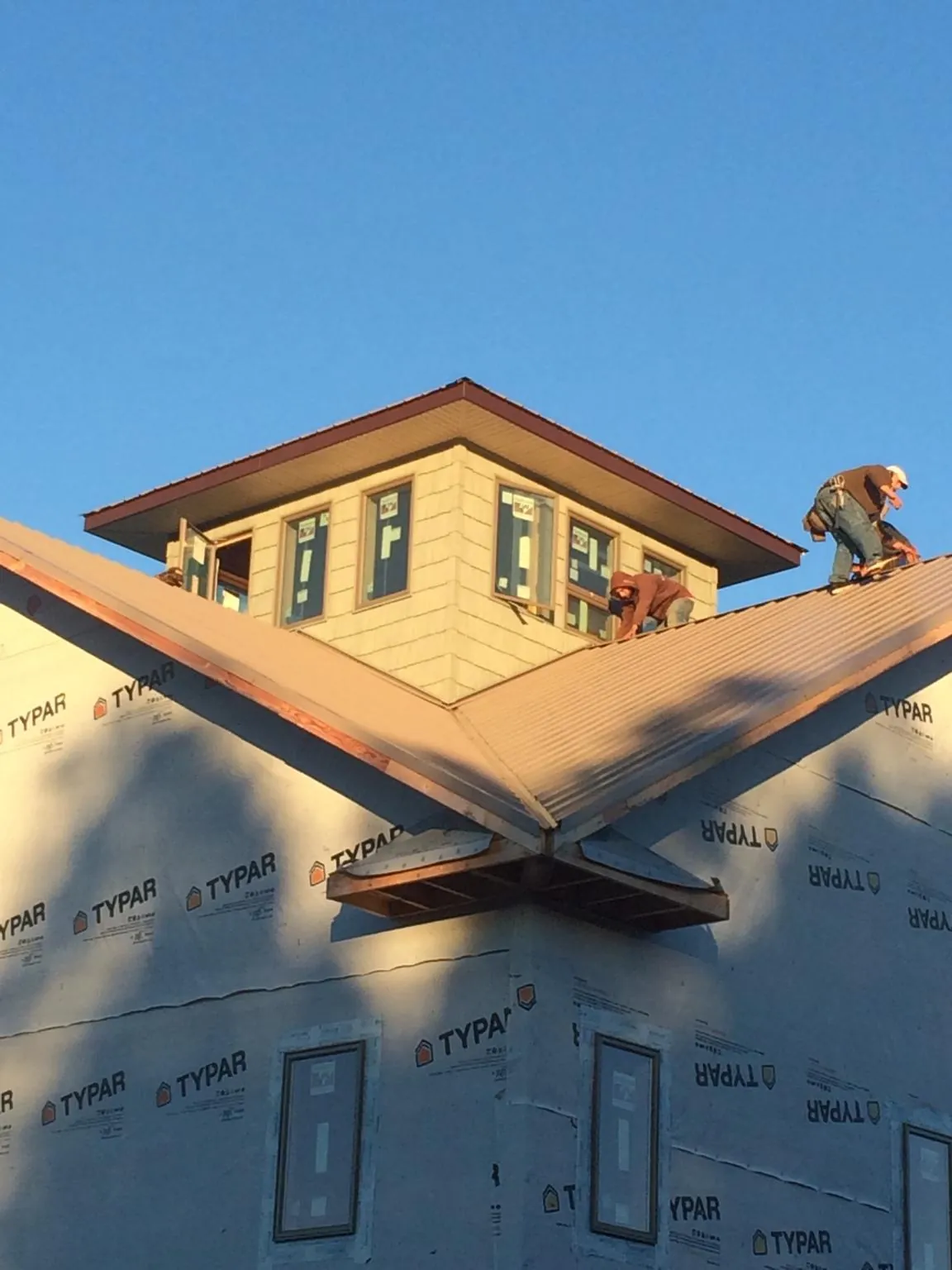 Roofers working around a rooftop cupola on a new metal roof at sunset — Roof Waterproofing in Sisters by Roofing Brothers